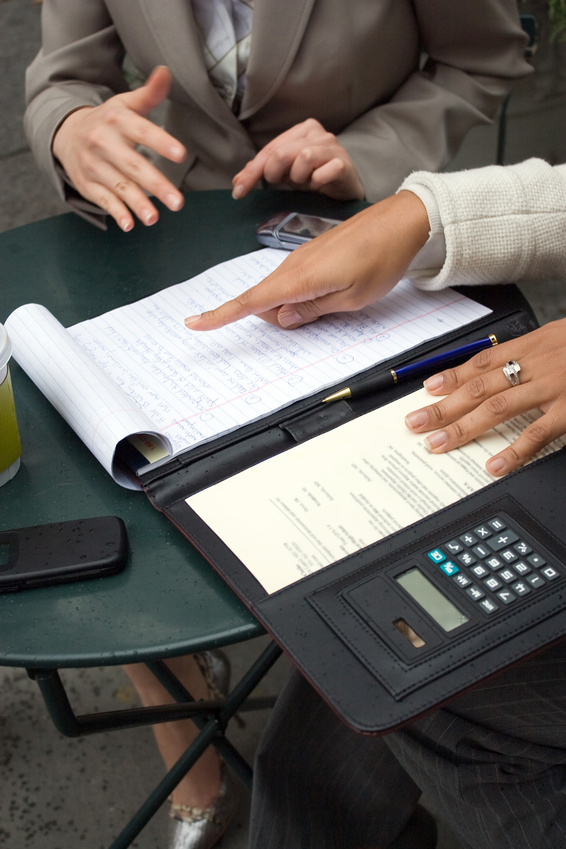 Two women having a discussion and sharing information during a business meeting. Shallow depth of field.