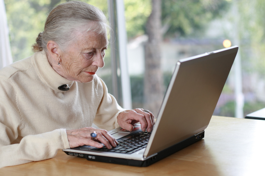 Elderly lady typing on laptop. Shallow DOF