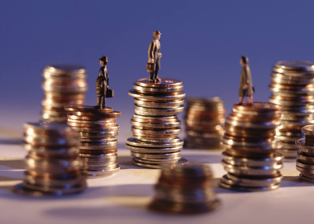 miniature woman standing over a pile of coins