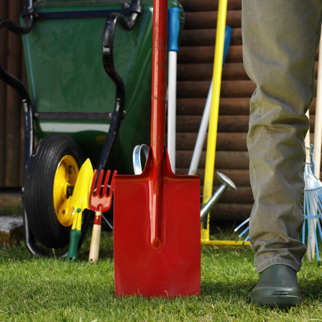 Leg of a Man Standing with a Shovel in a Yard