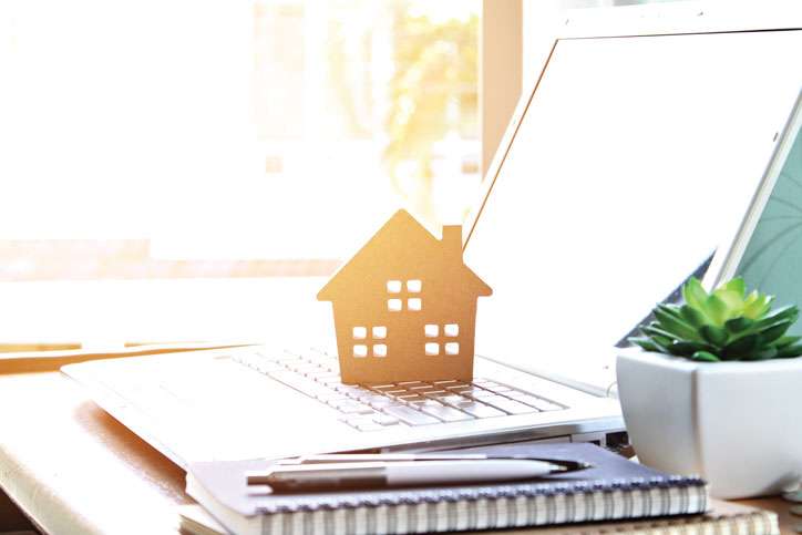 Wood house model sitting on laptop