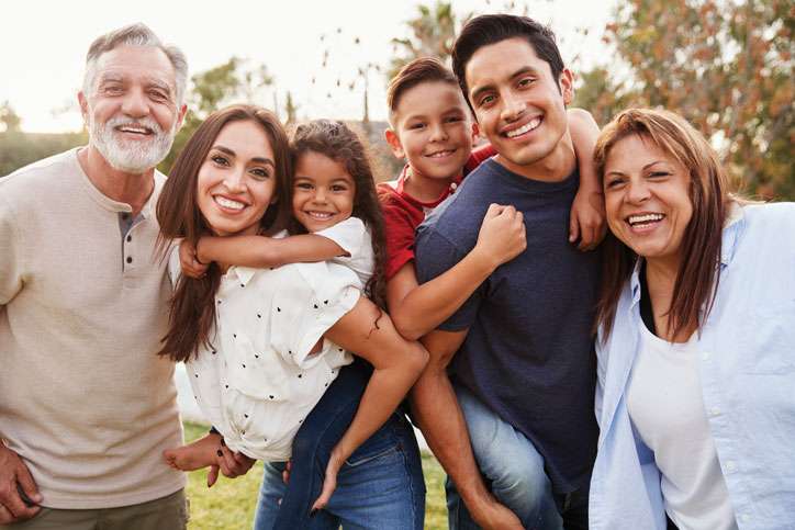 Three generation Hispanic family standing in the park, smiling to camera