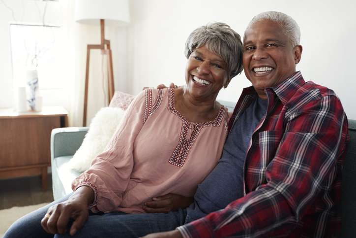 Portrait Of Loving Senior Couple Relaxing On Sofa At Home