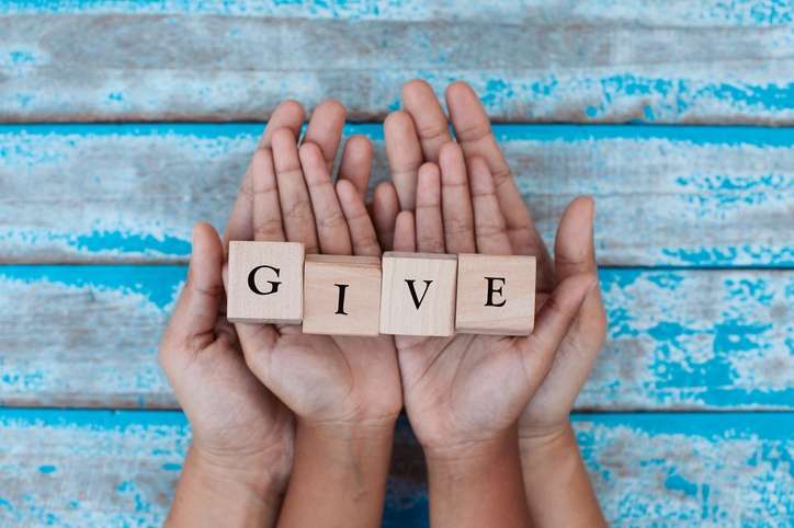 Giving to charity concept: Alphabet letter wooden blocks with words GIVE in child and parents hands