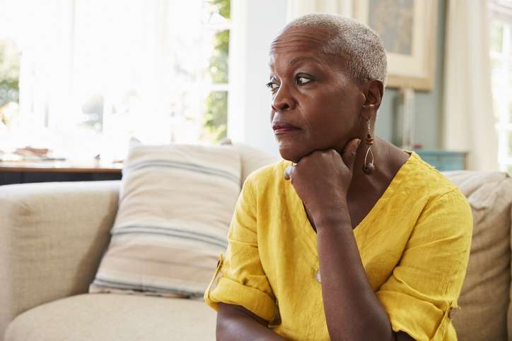 Senior Woman Sitting On Sofa At Home thinking about Social Security