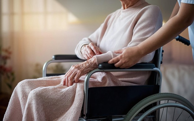Elderly man supported by caregiver during nursing facility discharge
